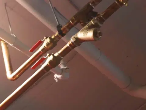 Open basement plumbing rough-in with exposed pipes for index in Stanton