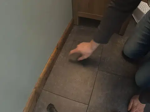 Installer setting a drain opening in tiled bathroom floor for index in Stanton