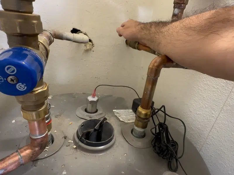 Plumber removing a depleted anode rod from water heater top for how long do water heaters last orange county in Stanton shown from a different service angle