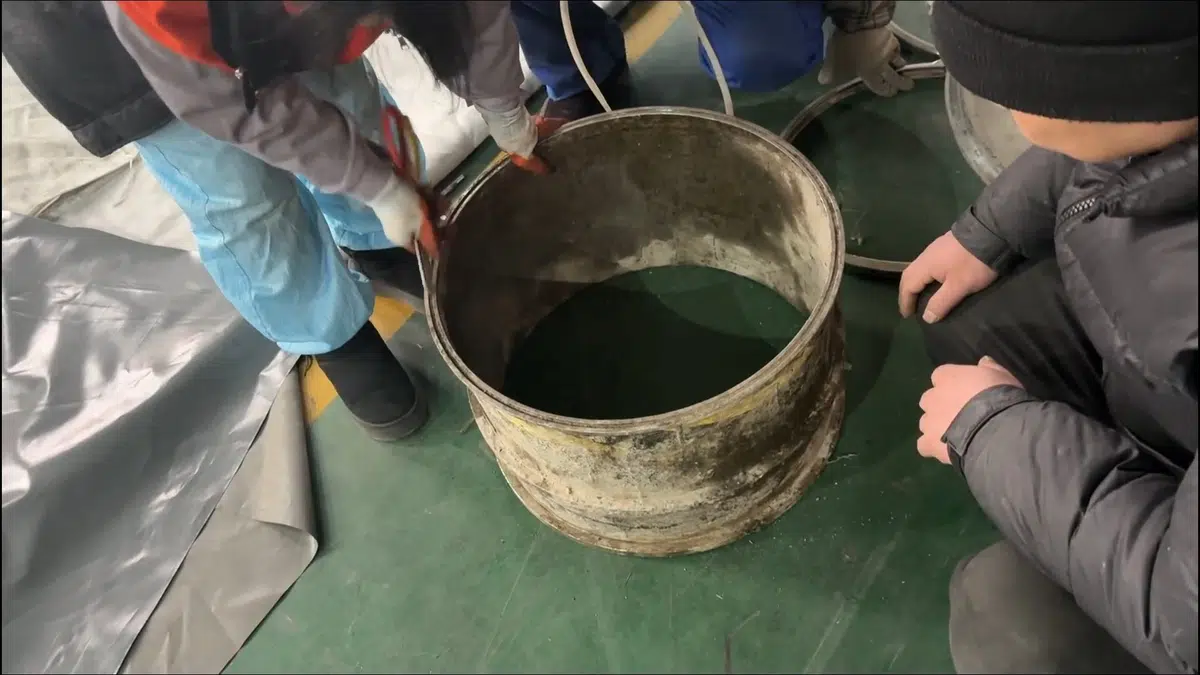 Technicians inspecting bucket of drain sludge during cleanup for tina park area in Tina Park Area, Stanton