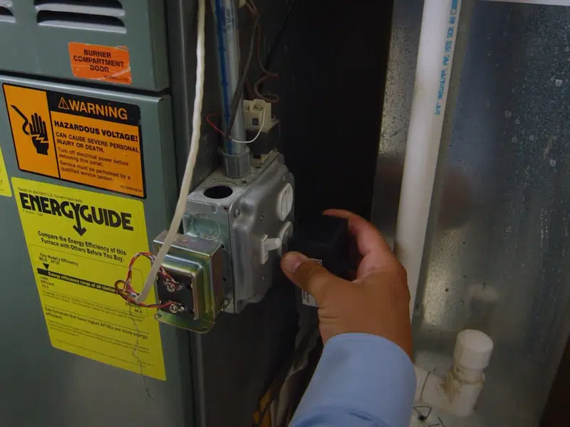 Hand checking water heater gas control label and valve area for water heater installation replacement in Stanton