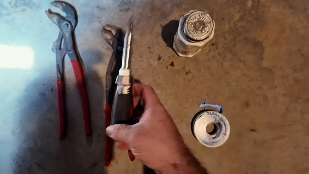 Hand holding gas shutoff parts beside water heater for water heater installation replacement in Stanton