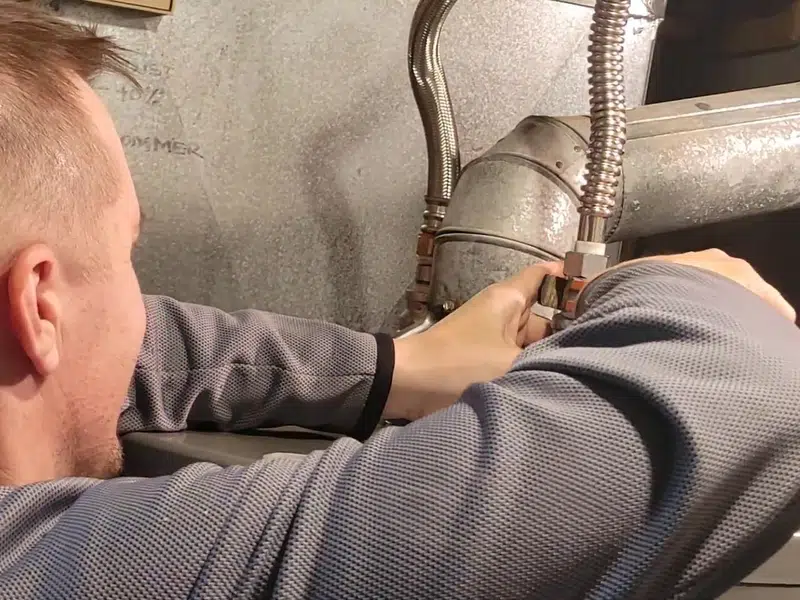 Technician working behind water heater on copper line for rental property water heater requirementslifornia in Stanton