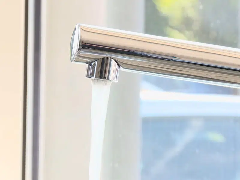Chrome kitchen faucet in front of bright window for water softener in Stanton