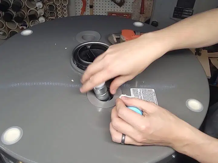 Hand placing warning label on new water heater top for water heater repair in Stanton