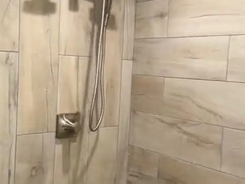 New tiled shower wall and valve trim in bathroom for shower bathtub installation in Stanton