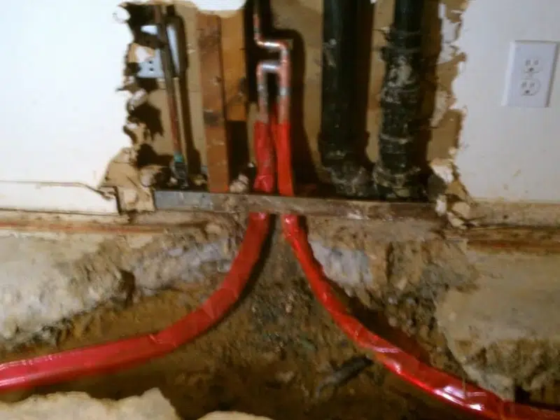 Red corrugated sleeve and pipe connections below fixture for repiping in Stanton