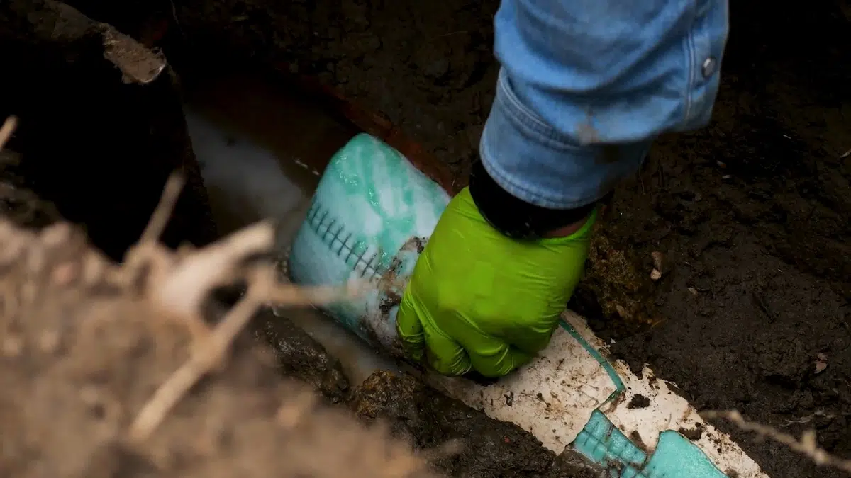 Technician feeding liner material into underground sewer access for south stanton in South Stanton