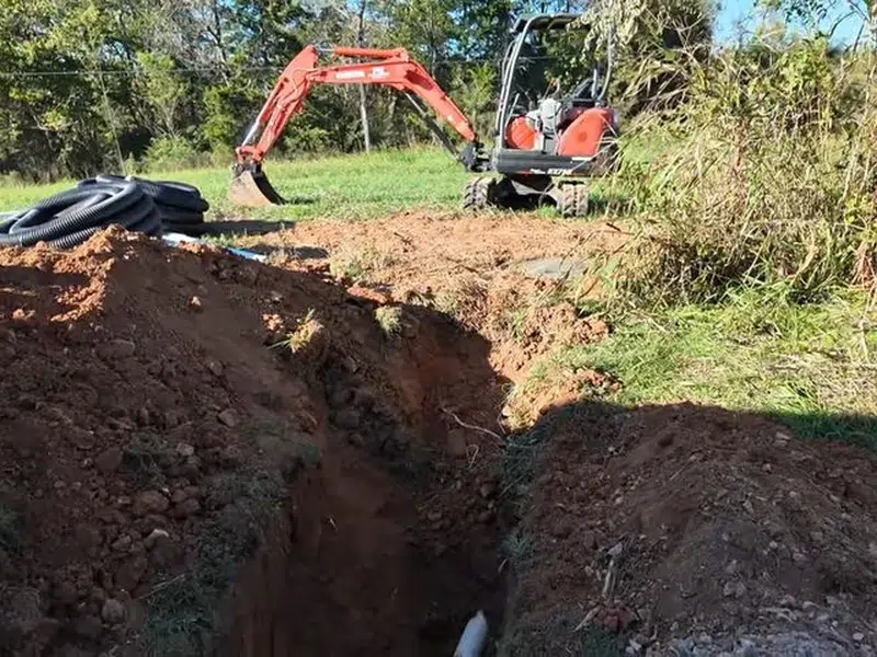 Excavator digging trench for underground sewer replacement for sewer line replacement in Stanton