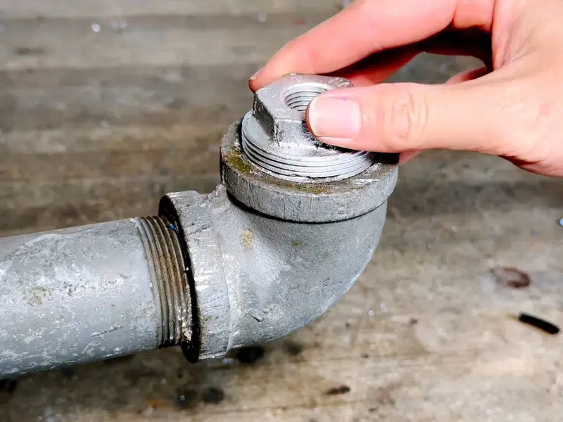 Hand loosening stuck metal cleanout plug on cast iron pipe for home page in Stanton