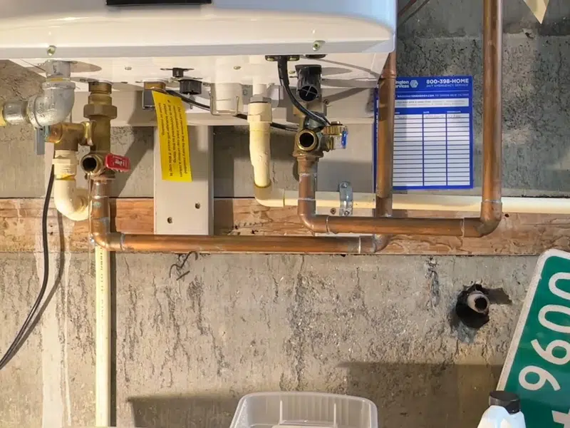 Tankless water heater service hoses connected below unit for tankless water heater in Stanton
