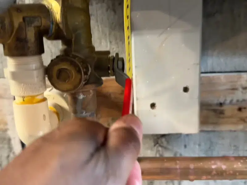 Technician opening a tankless water heater service valve for slab leak detection repair in Stanton
