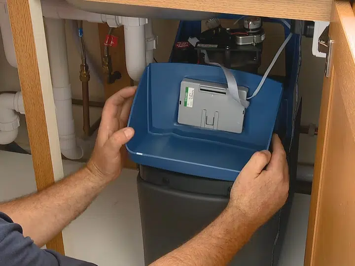 Technician working below sink on water softener connections for hose bib outdoor faucet in Stanton