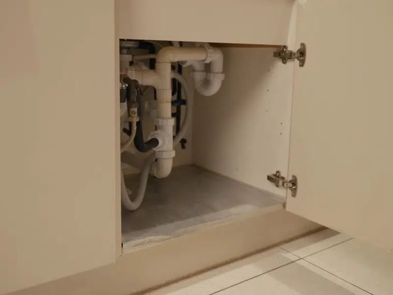 Empty under-sink cabinet with water line connection for pool leak detection repair in Stanton