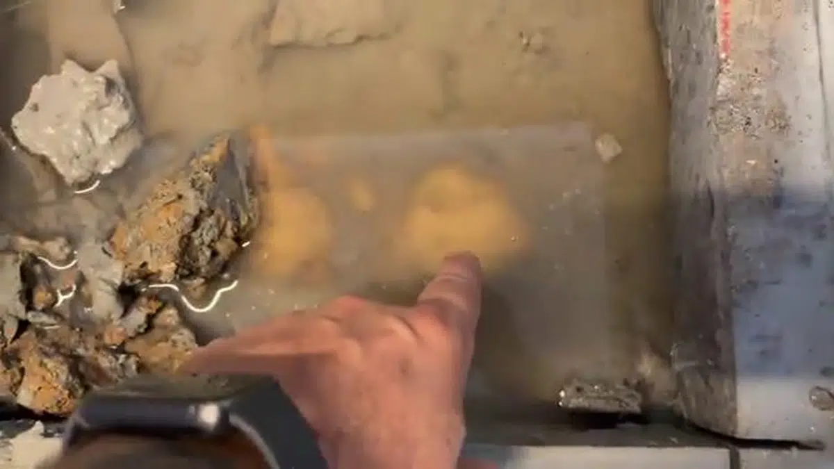Hand pointing to wet concrete around slab pipe leak for 24 7 emergency plumber in Stanton